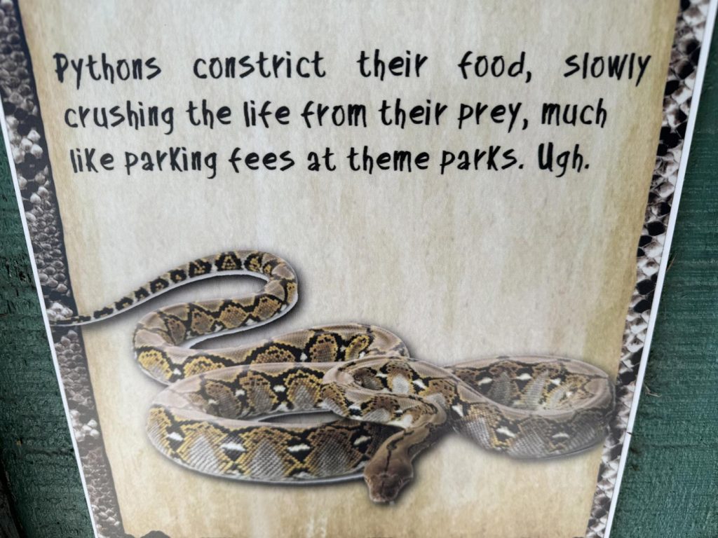 Python sign at Gatorland reads "Pythons constrict their food, slowly crushing the life from their prey, much like parking fees at theme parks."